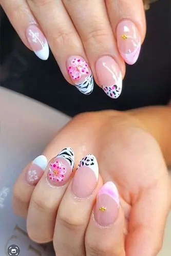 A close-up photograph displays hands with almond-shaped nails featuring a variety of intricate designs, including white French tips, pink floral accents, and black-and-white animal print patterns.
